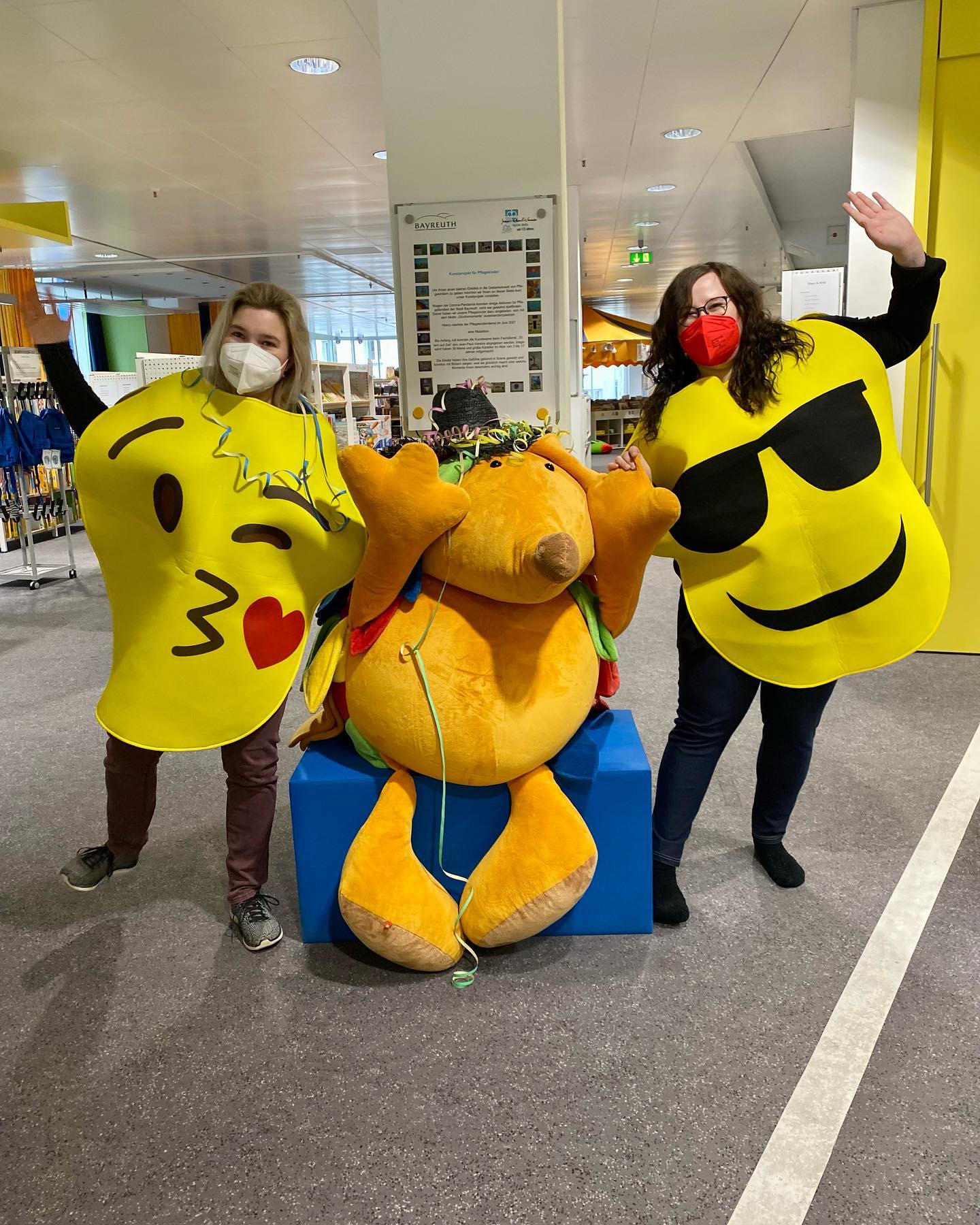 zwei junge Frauen mit Emoji Kostümen feiern fasching mit einem großen Plüschigel