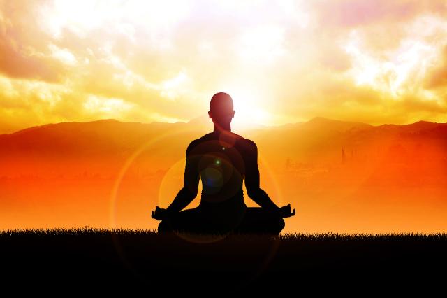 Frau sitz in Yogahaltung vor Sonnenuntergang