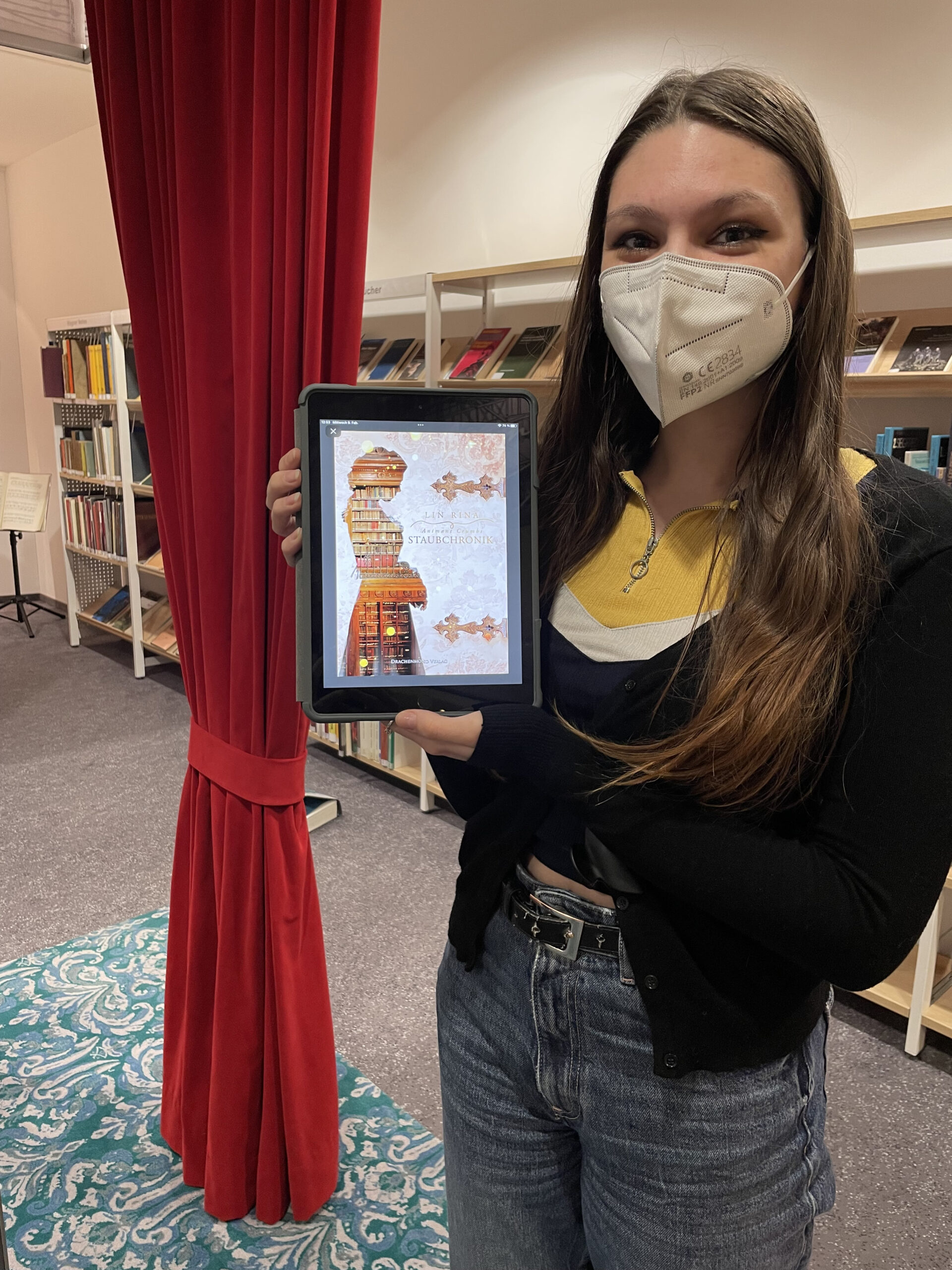Junge Frau hält ein iPad hoch, das ein Buchcover anzeigt