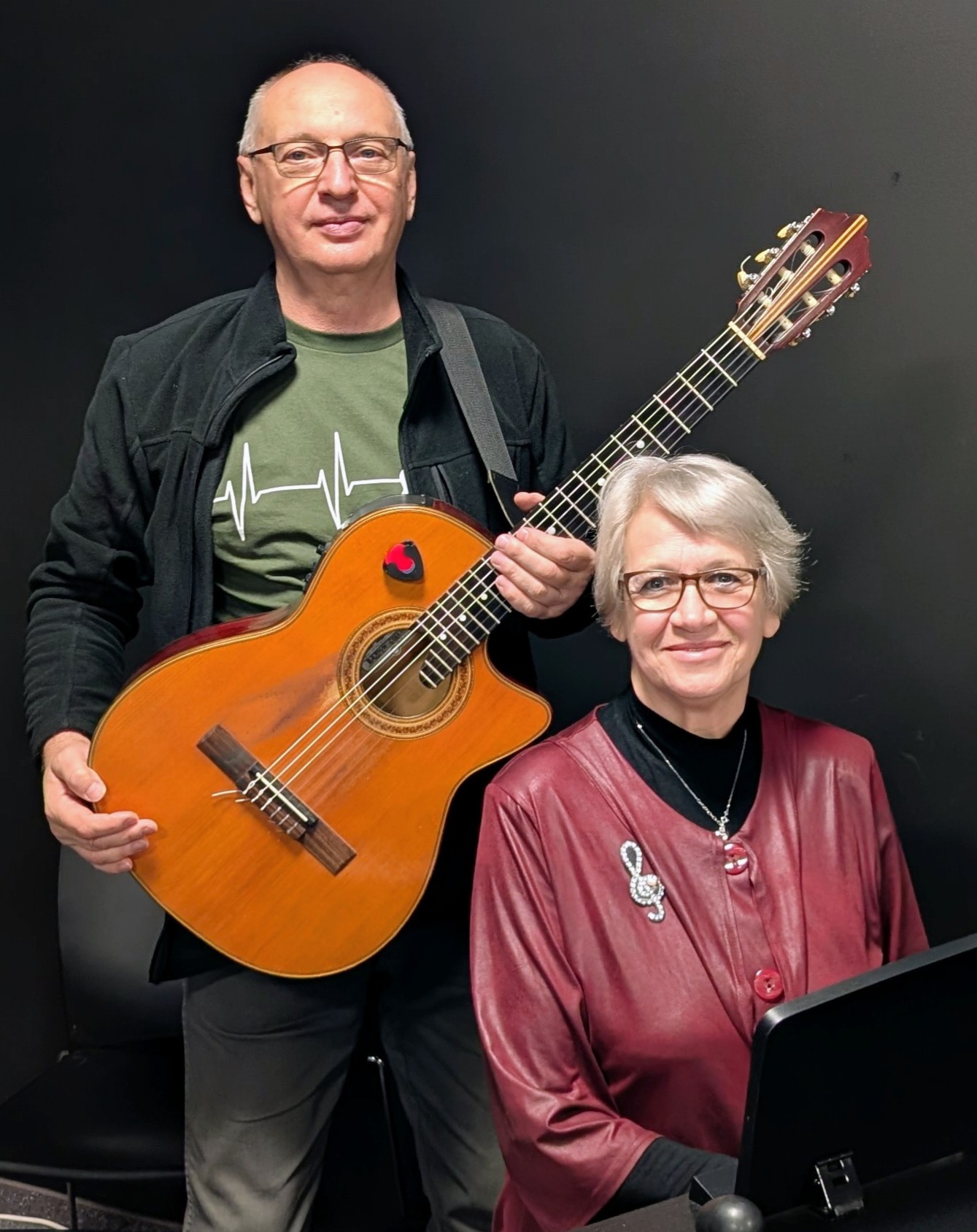 Ein Mann mit Gitarre und eien Frau, die vor ihm sitzt.