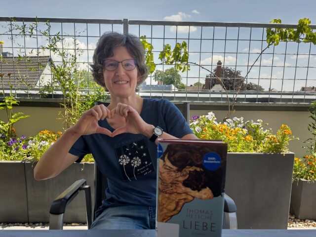 Frau Ring setzt auf der Dachterasse mit dem Buch, das sie vorstellt.